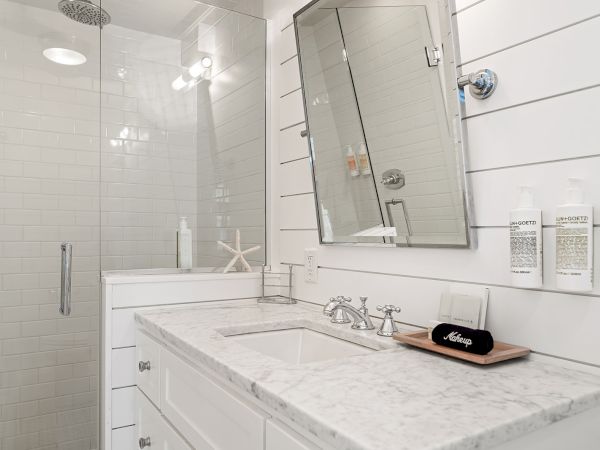 A modern bathroom with a marble countertop, wall-mounted toiletries, and a glass shower enclosure.