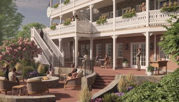 People are socializing on an outdoor patio with seating areas, surrounded by greenery and a grand staircase leading to upper balconies.