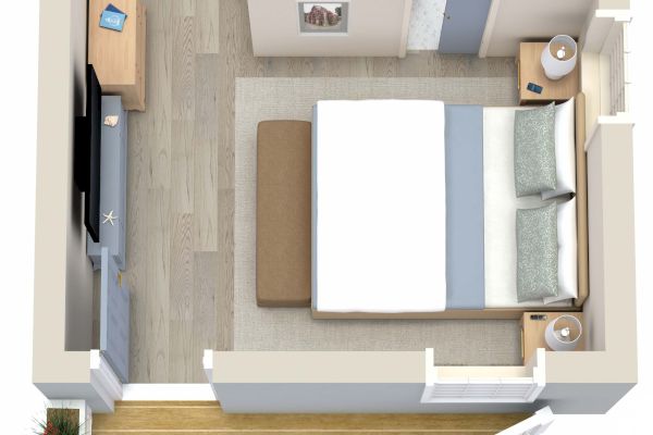 This image shows a small bedroom with a double bed, nightstands, a television, a desk, a bathroom, and a small outdoor deck along one wall.