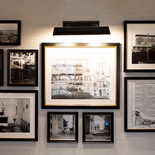 A wall display of framed black-and-white photos and a document, with a light fixture above, creates a historical gallery-like setting.