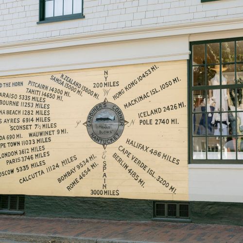A seaside wall compass mural shows world cities and nautical mile distances (e.g., Valparaiso, London, Cape Verde) around the Horn.