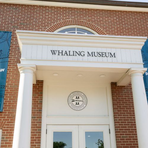 Entrance to the Whaling Museum with banners reading &ldquo;The Wider World & Scrimshaw&rdquo; for a featured exhibition.