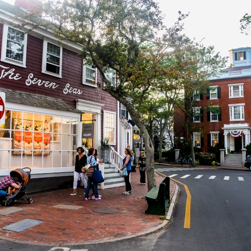 A charming street corner with a red building labeled "The Bean Boss," people gathered outside, and historic architecture visible in the background.