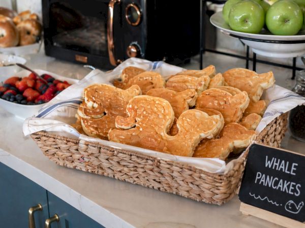 A basket of heart-shaped pancakes sits on the counter, with a chalkboard sign reading &ldquo;WHALE PANCAKES&rdquo; nearby.
